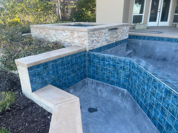 A blue tiled swimming pool with steps leading up to it