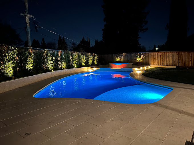 A backyard with a swimming pool at night