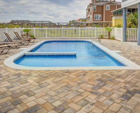 A small swimming pool with a deck and chairs around it