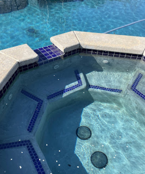 A hot tub in a pool surrounded by rocks