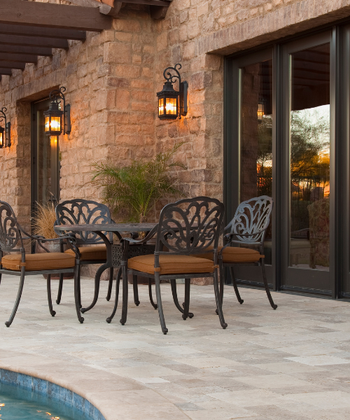 A patio with a table and chairs next to a pool