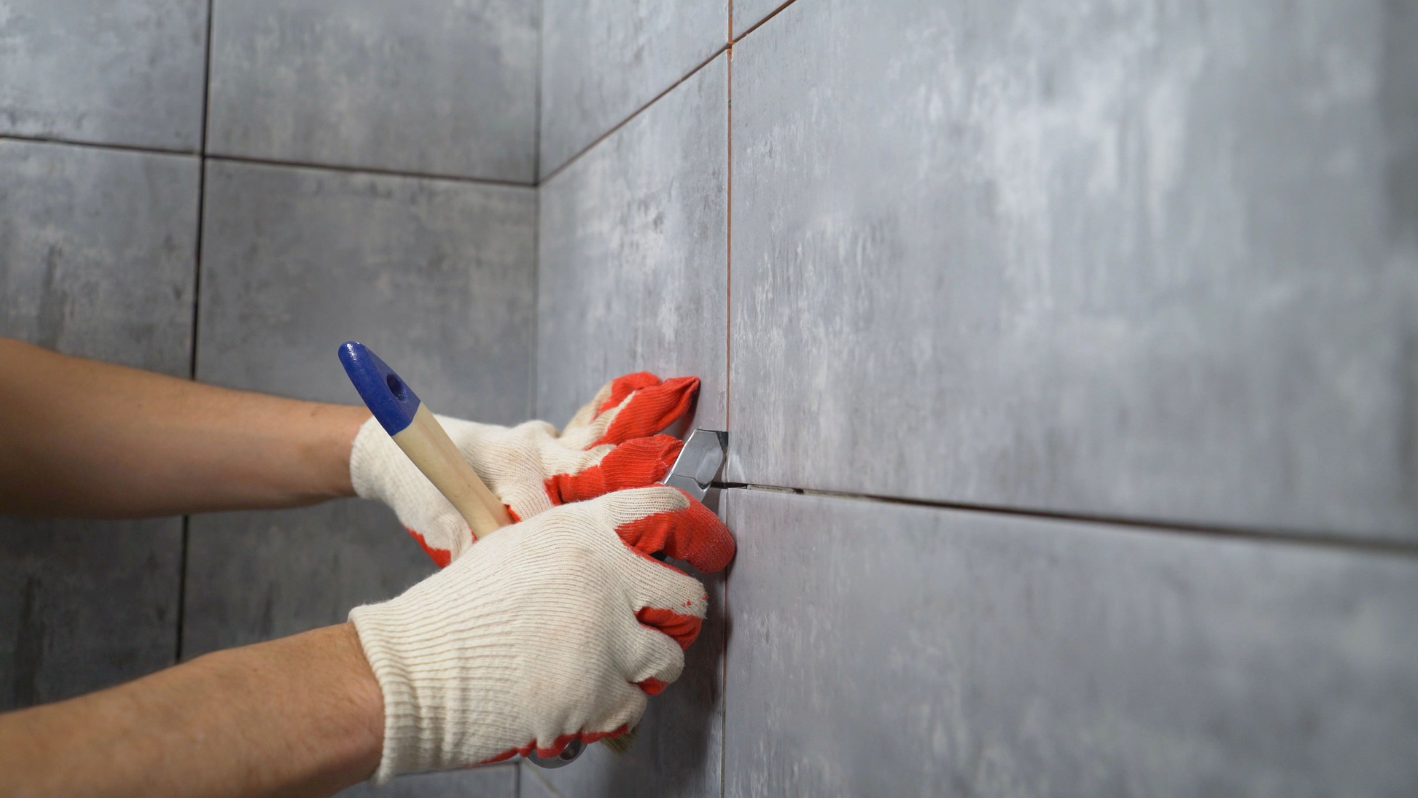 A person with gloves and gloves is cleaning a tile wall