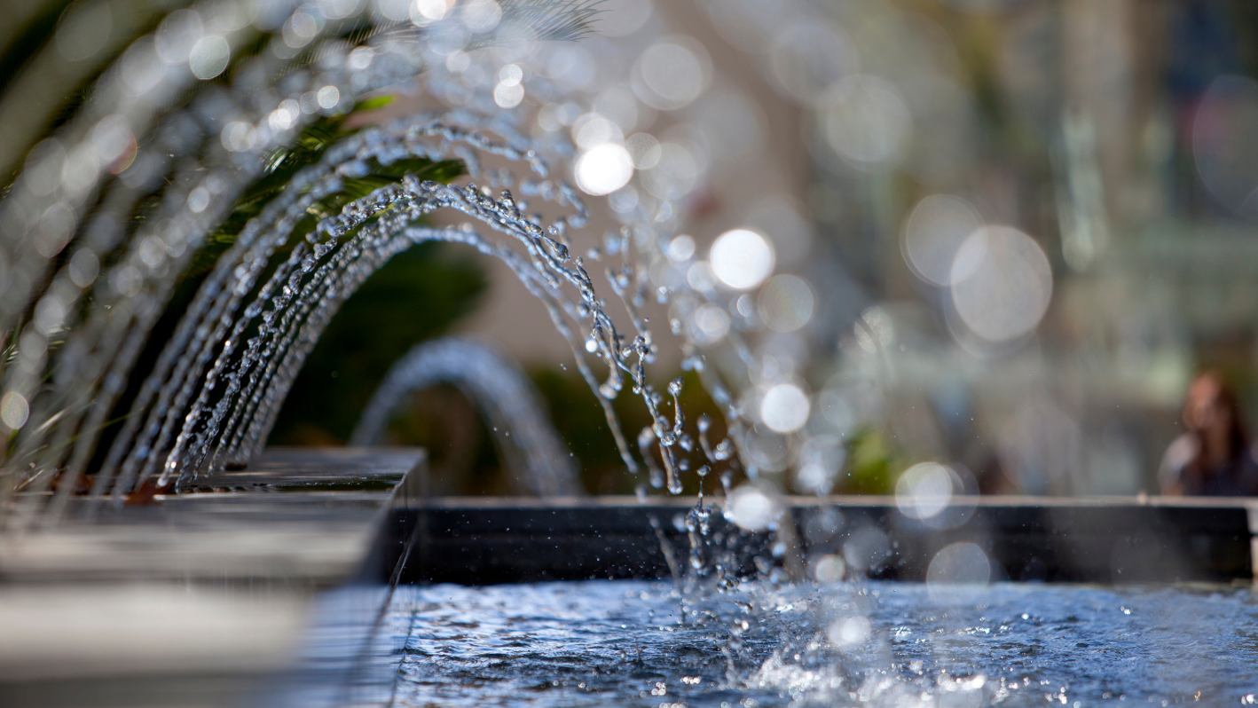 A close up of a water fountain with people in the background